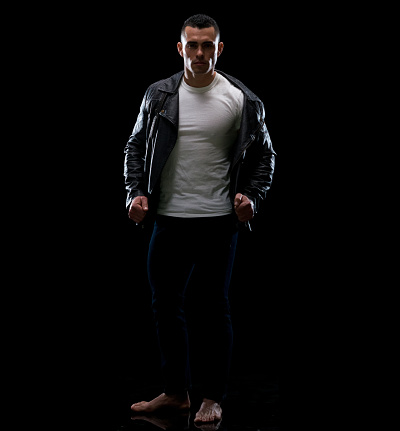 Full length of aged 20-29 years old latin american and hispanic ethnicity male in front of black background wearing jeans who is serious