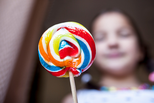 Child girl with colorful big lollipop. Selective focus. Unhealthy food for children concept