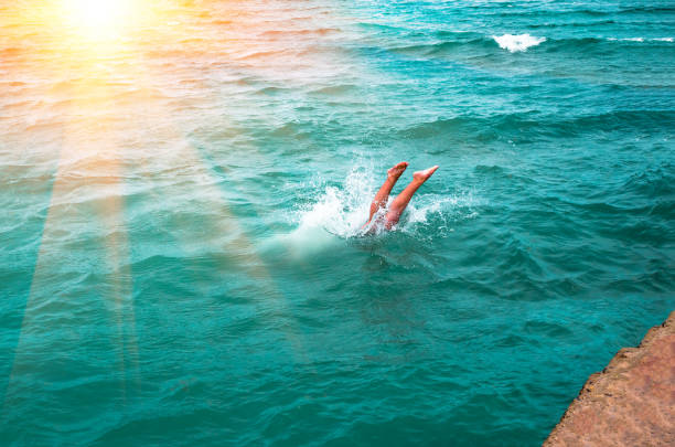 A young man's legs disappearing as he dives into the in a refreshing sea, ocean, On a hot summer day