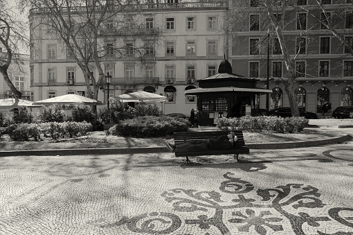 Lisbon, Portugal - February 18, 2020: A man takes a nap on a park bench in the Avenida da Liberdade avenue in Lisbon downtown.