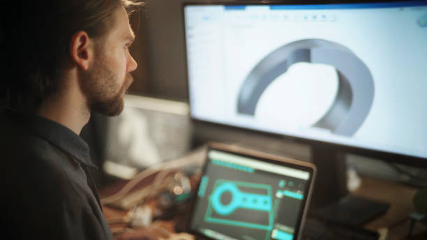 Drawing Close up stock photo of a long haired, bearded young man working at a wide computer screen. He’s working on software designing a circular component. computer aided design stock pictures, royalty-free photos & images