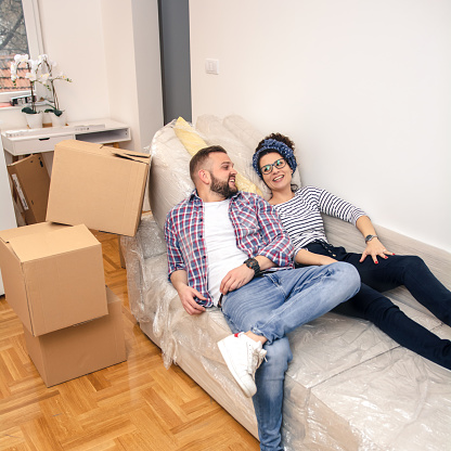 A young, cheerful, caucasian couple is having fun and playing in their new home.