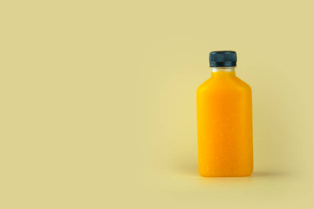 istock Natural pure orange juice packed in plastic bottles on yellow background 1246342843