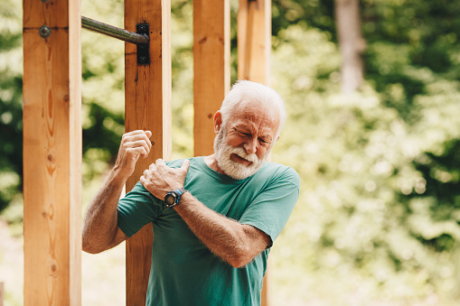 Senior man suffering with shoulder pain during workout