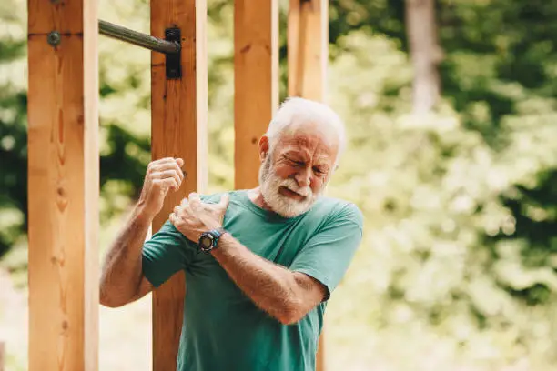 Photo of Senior man suffering with shoulder pain during workout