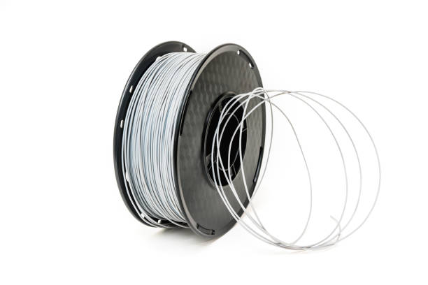 istock 3D Printer Plastic Filament. Spool of grey thermoplastic wire for 3D printing close up isolated on white background 1246346327
