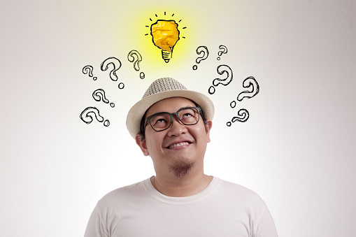 Young Asian man looked happy thinking and looking up, having good idea. With bulb lamp doodle over his head