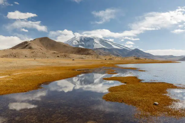 Lake Karakul, Xinjiang / China - Oct 2, 2017: With reflection of Muztagh Ata in the water. High plateau at the pamir mountains. Along the Karakorum Highway. The elevation of Muztagh Ata is over 7000 meters (7.546 meters)