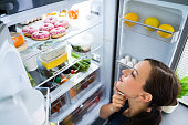 Hungry Woman Looking For Food In Kitchen