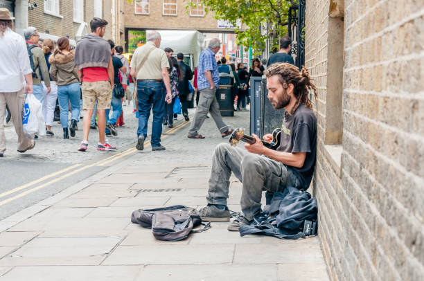 London, England, UK- 31 August 2014: \tStreet musician playing the guitar in Brick Lane.  The market sells a diverse range of items, from antique books to eight-track cartridge decks, and for many years it hosted a stall selling nothing but rusty cog wheels. The market has always been popular with and much photographed by art students, and bargain hunters from across London value it greatly.