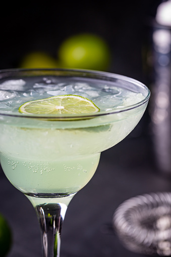 margarita cocktail with lime in a glass on dark background