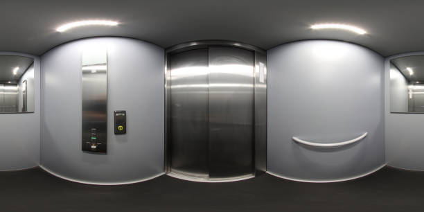 360 Degree panoramic sphere photo taken inside a metal elevator lift in the UK showing the closed metal doors with a large mirror on the back wall stock photo