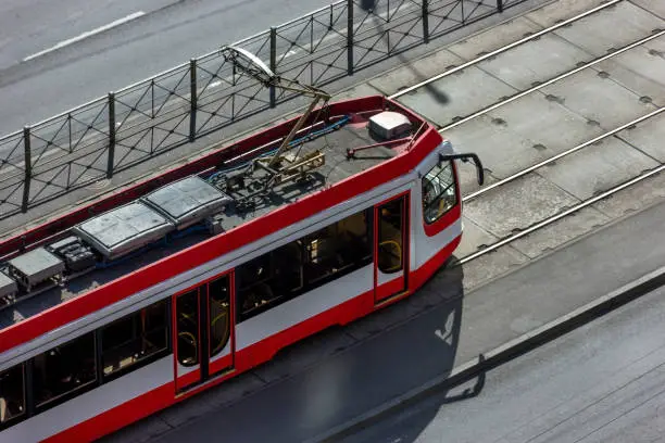 Photo of The urban red modern tram moves along the train track. Ecological, social transport of citizens