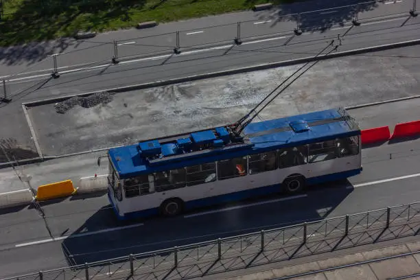 Photo of Blue and white urban trolleybus on the streets of a modern city. Top view of the road