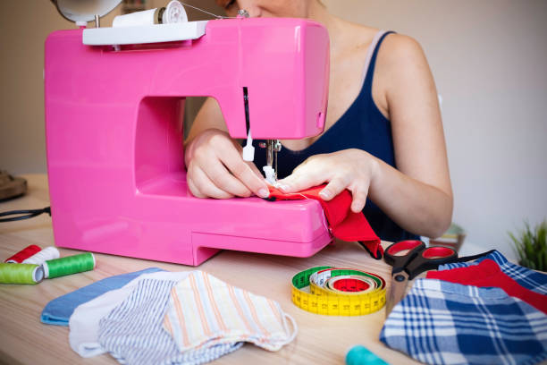 istock Seamstress working with sewing machine making trendy face medical mask for preventing and stop coronavirus spreading - Homemade manufacturing concept - Reuse of used clothes - Main focus on fingers 1246373695