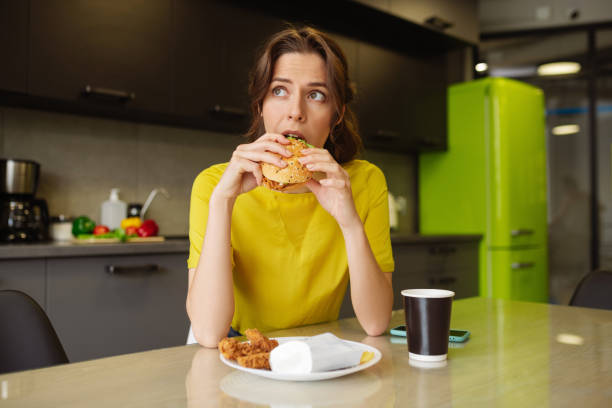 istock Dark-haired girl biting off a burger looking to the side 1246395288