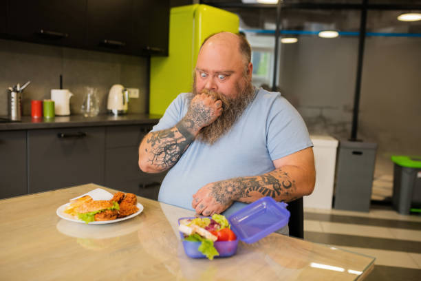 Thinking man with funny grimace near the food Uncertainty. Thinking fat man with funny grimace fist with tattoos near his mouth, staring with big eyes at food arm tattoo ideas for men pictures stock pictures, royalty-free photos & images