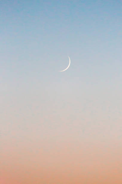 istock Crescent moon rising after sun set, with a peach and blue coloured sky 1246413964
