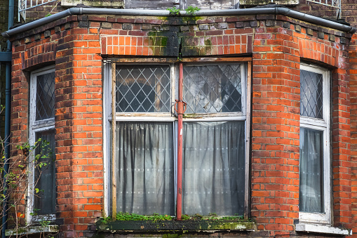 Row of old windows with shutters and flower boxes with geraniums