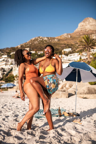 Two friends at the beach. Two young smiling African females enjoying at the beach black women in bathing suits stock pictures, royalty-free photos & images