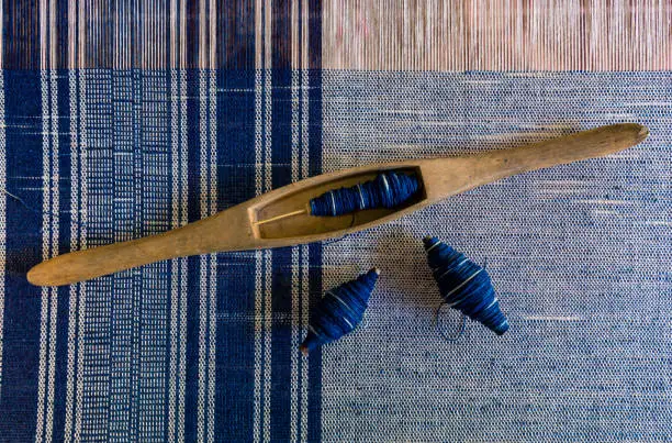 Crafts and craftsmanship. Traditional Isan Thai Cotton indigo weaving. Woven cotton. Fabric cotton texture. Bobbin and thread winder. Shuttle weaving. Weaving work.