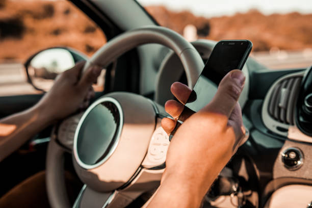 istock Man driving a car holding steering wheel with and without mobile phone 1246468372