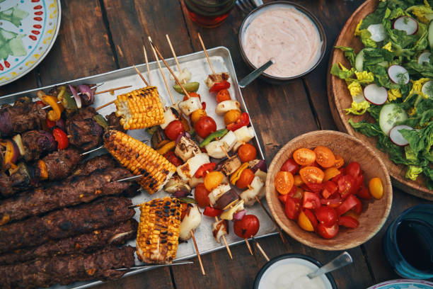 istock Preparing Lamb, Beef and Vegetable Kebab with Green Salad Outside 1246479718