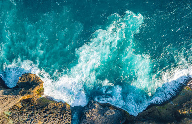 Top down of Indian Ocean and rocky shores Beautiful scenic aerial landscape of rocky shores, beaches, tide pools and cliffs of Nusa Penida island, Bali, Indonesia. Stormy waves, aquamarine ocean water and sunny day. kelingking beach stock pictures, royalty-free photos & images