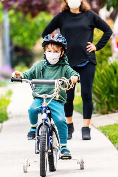 istock Little child boy riding a bicycle wearing a protective face mask 1246484530