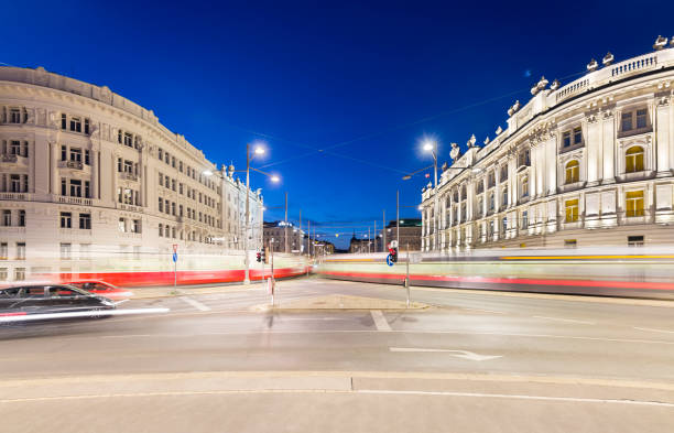 Night shot of blurred crossing trams at Schwarzenbergplatz with traffic and night blue sky in Vienna, Austria