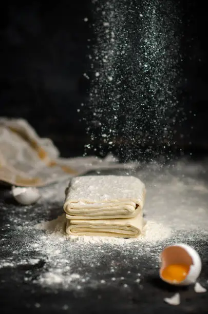 Photo of Homemade raw puff pastry on black background