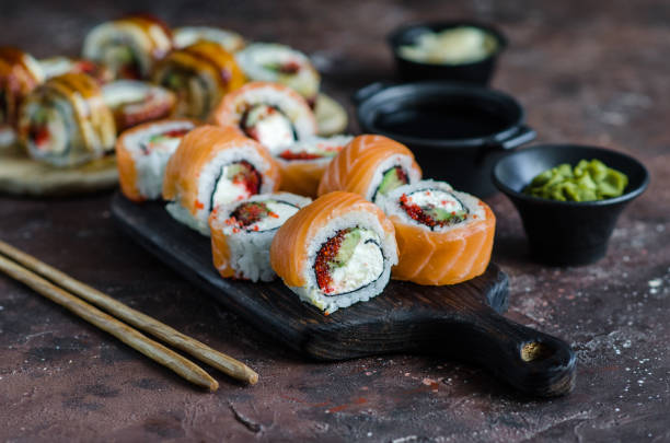 istock Different Sushi rolls with red fish and eel, wasabi and ginger on a plate on wooden background. 1246484742