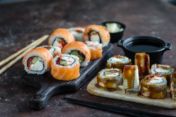 istock Different Sushi rolls with red fish and eel, wasabi and ginger on a plate on wooden background. 1246484769