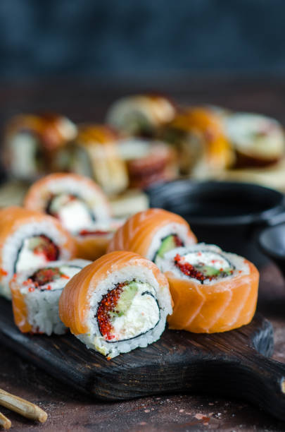 different sushi rolls with red fish and eel, wasabi and ginger on a plate on wooden background. - food sushi seafood maki sushi imagens e fotografias de stock