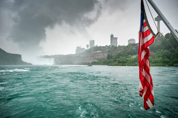 United States flag with the Niagara Falls in the background United States flag with the Niagara Falls in the background, cloudy day and surreal atmosphere rochester new york state stock pictures, royalty-free photos & images