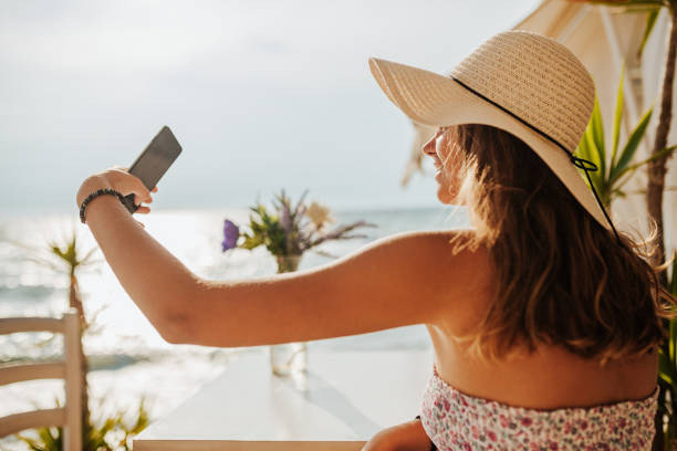 istock Smiling woman taking selfie at beach cafe 1246548032
