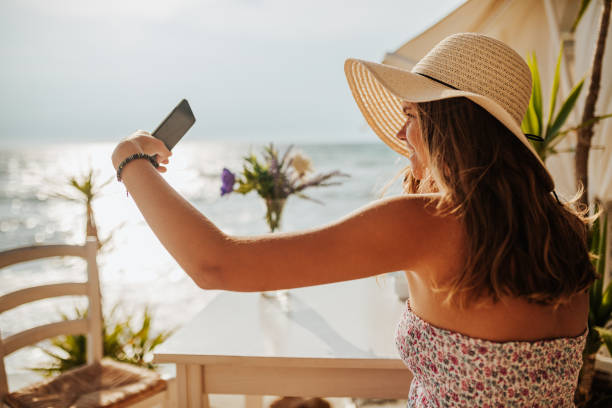 istock Young woman taking selfie at beach cafe 1246548061