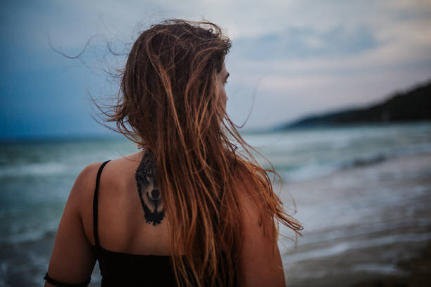 Relaxed young woman at the seaside admiring the sunset over water