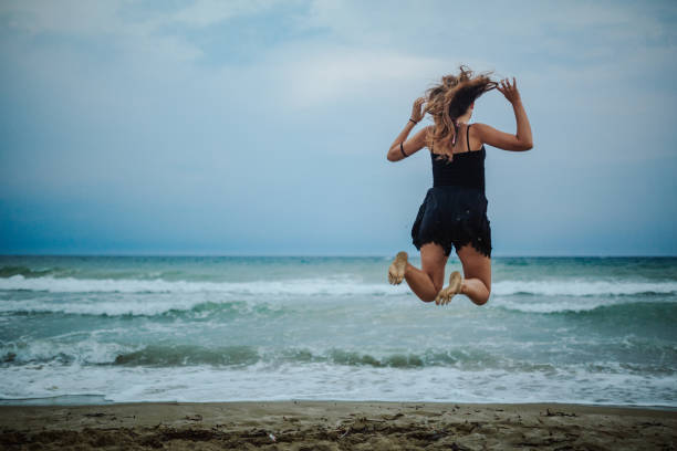 istock Happy girl jumping on the beach at sunset 1246548169