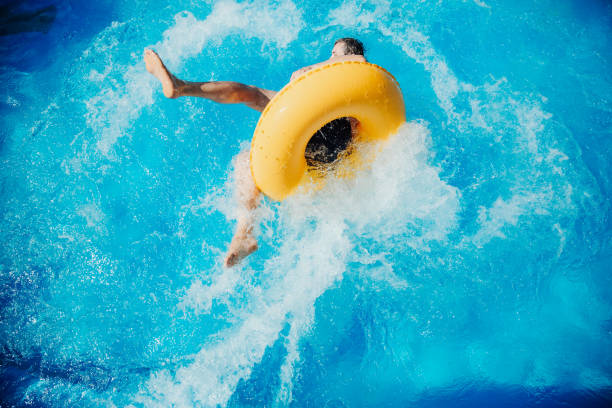 hombre alegre divirtiéndose deslizándose en el parque acuático - floating on water swimming pool men water fotografías e imágenes de stock