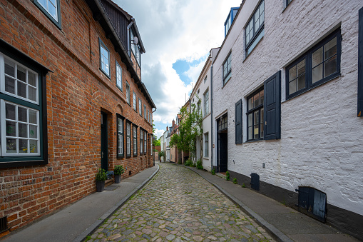 Narrow cobblestone alley with historic residential buildings in the old town of the hanseatic city Luebeck, Germany, selected focus