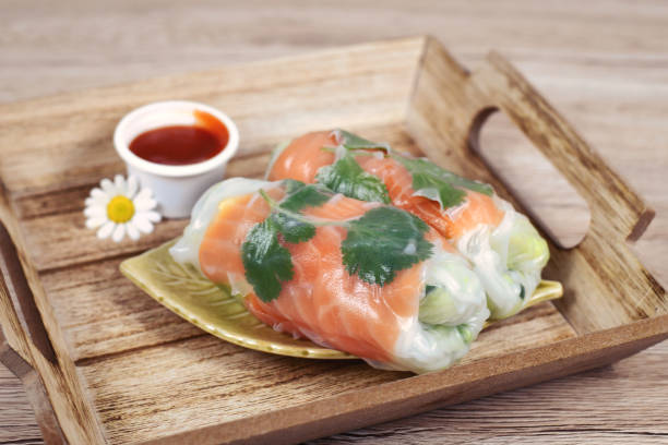 traditionelle vietnamesische frühlingsrollen gefüllt mit lachs, avocado, salat und reisnudeln auf holztablett - rolled up rice food vietnamese cuisine stock-fotos und bilder