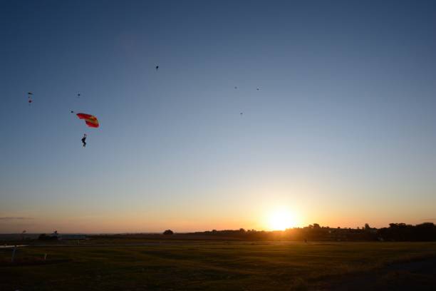 istock Skydivers and sunset in green field 1246555944