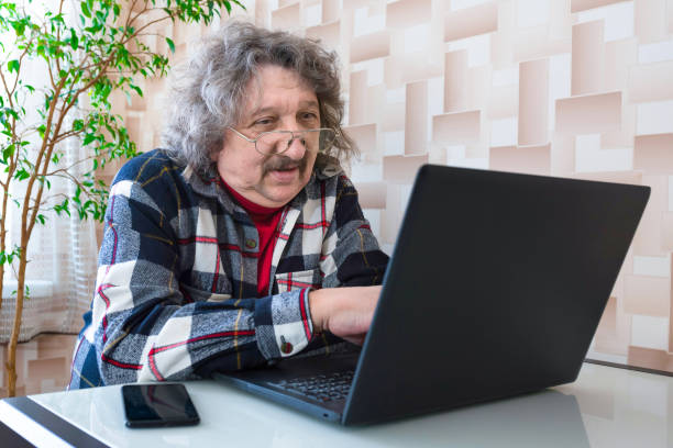 a portrait of an elderly 60 or 70-year old man working at the computer, a close-up. - 60 70 year old imagens e fotografias de stock