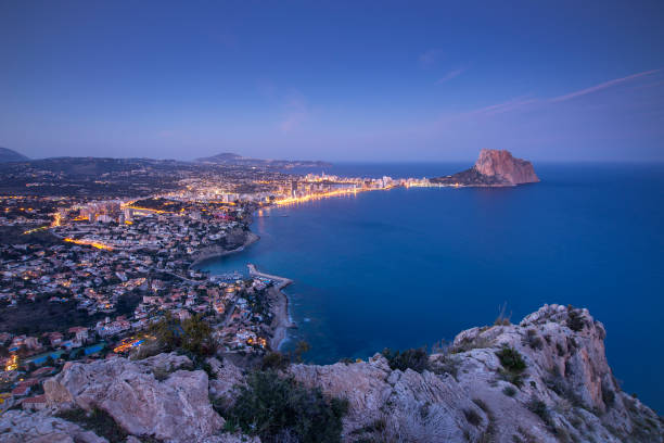Sunrise in the hill of Toix, Marivilla in Calpe, in the blue hour with lighting of the lights of the town of Calpe and the rock of Ifach in the background.