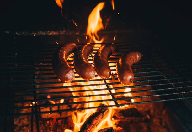 バーベキューでソーセージ肉を調理します。グリルに4つのソーセージ。夏の間にカントリーハウスの裏庭で屋外で食事の概念. - sausage bratwurst barbecue grill barbecue ストックフォトと画像