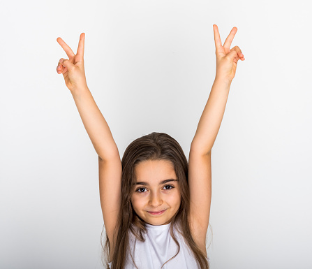 Young smiling girl wearing white t-shirt holding hands up with two fingers looking at camera