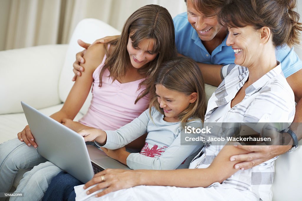 Familia de cuatro usando laptop y sonriendo - Foto de stock de 40-49 años libre de derechos