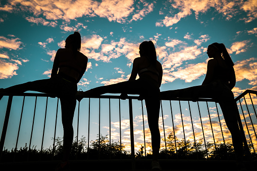 Silhouette of young fitness women stretching at sunset outdoor