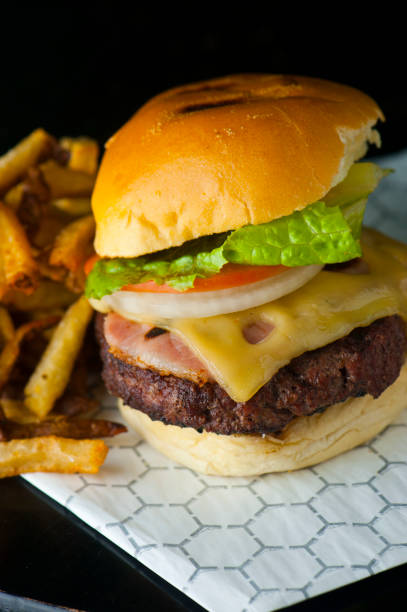 istock Hamburger with melted cheddar and Swiss cheese, Mac n cheese, bacon, fried egg, lettuce, tomatoes and onions. Served with crispy French fries. Classic American restaurant favorite. 1246642744